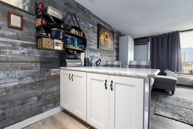 kitchen with white cabinetry, light hardwood / wood-style flooring, and a textured ceiling