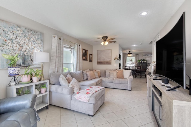 living room with a textured ceiling, ceiling fan, and light tile patterned floors