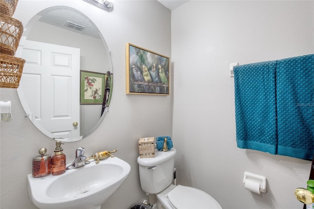 bathroom with a textured ceiling, toilet, and sink