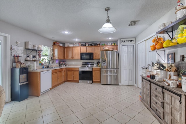 kitchen with a textured ceiling, light tile patterned floors, decorative light fixtures, stainless steel appliances, and sink