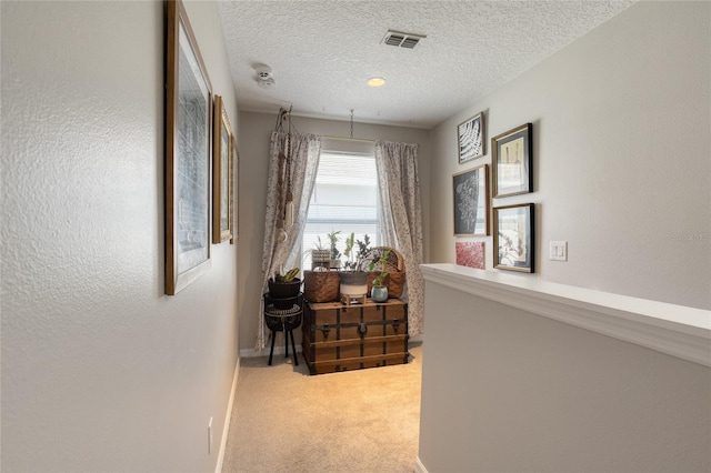 hallway with a textured ceiling and carpet flooring