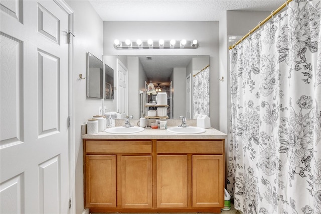 bathroom with a textured ceiling, vanity, and a shower with curtain