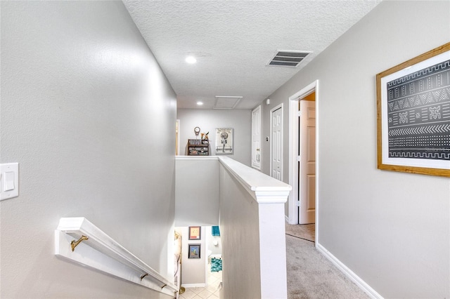 corridor with light colored carpet and a textured ceiling