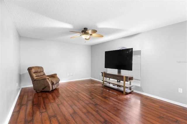 living area featuring dark wood-type flooring, ceiling fan, and a textured ceiling