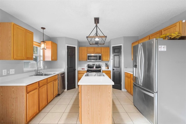 kitchen featuring appliances with stainless steel finishes, an island with sink, sink, and hanging light fixtures