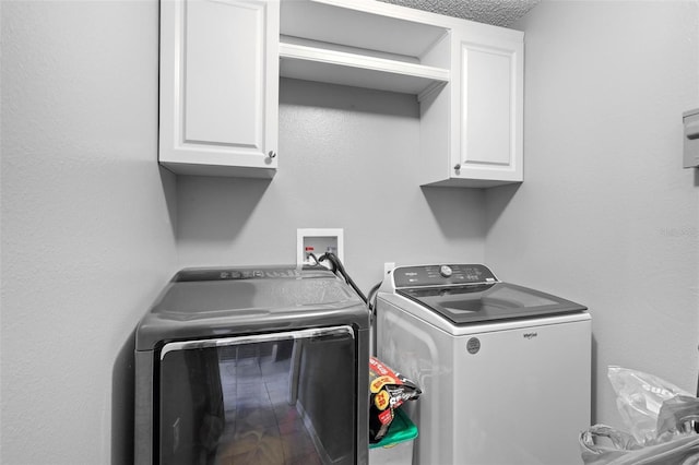 clothes washing area featuring washing machine and clothes dryer and cabinets