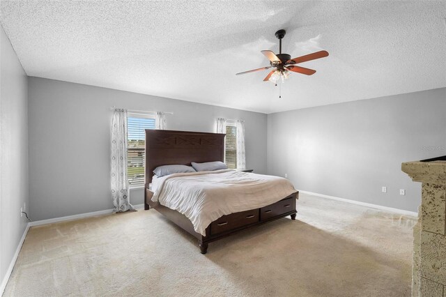 carpeted bedroom featuring ceiling fan and a textured ceiling