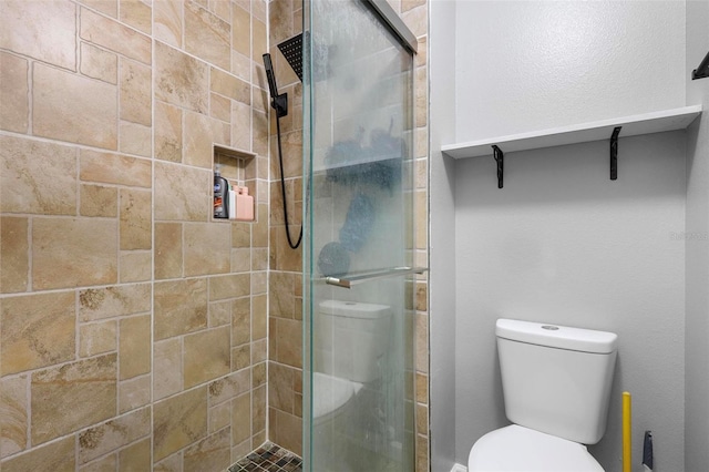 bathroom featuring toilet and a shower with shower door