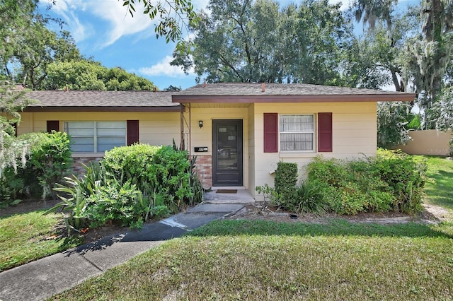 view of front of house featuring roof with shingles and a front yard