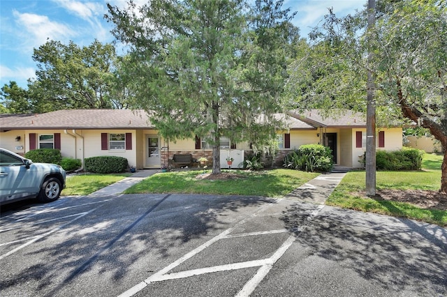 ranch-style home featuring roof with shingles and a front yard