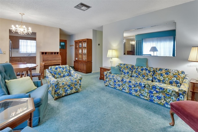 carpeted living room featuring an inviting chandelier and a textured ceiling