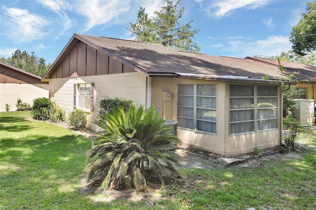 view of home's exterior with a shingled roof, a lawn, and board and batten siding