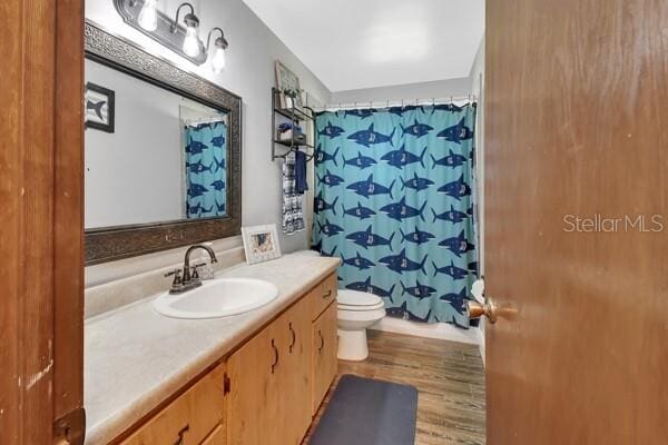 bathroom featuring vanity, toilet, a shower with shower curtain, and hardwood / wood-style flooring