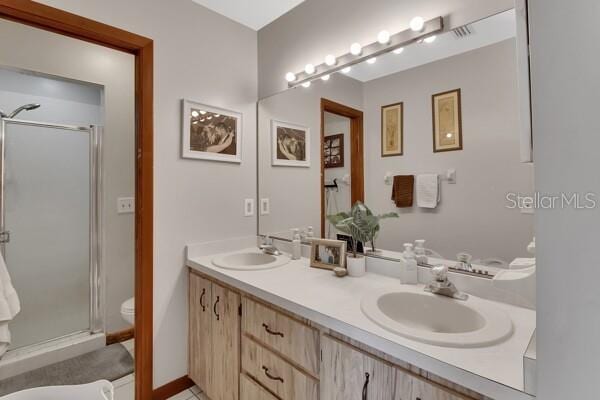 bathroom featuring vanity, a shower with shower door, and toilet