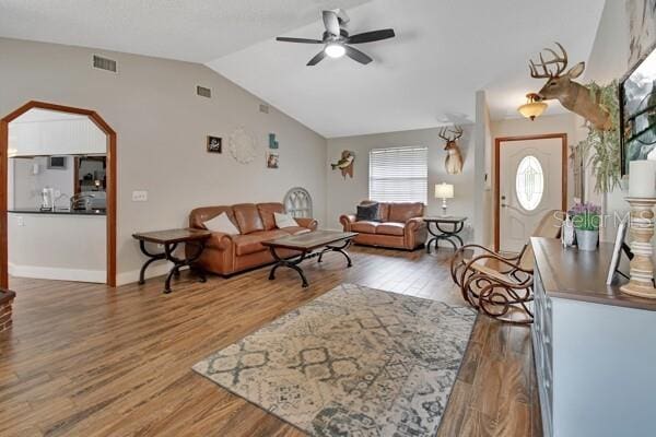 living room featuring ceiling fan, hardwood / wood-style floors, and vaulted ceiling