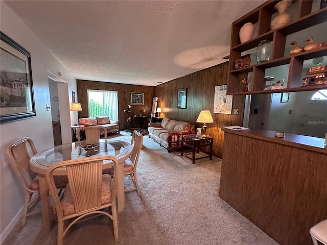 dining room featuring a textured ceiling, wood walls, and carpet flooring