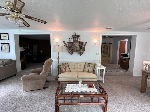 living room with a textured ceiling, carpet flooring, and ceiling fan