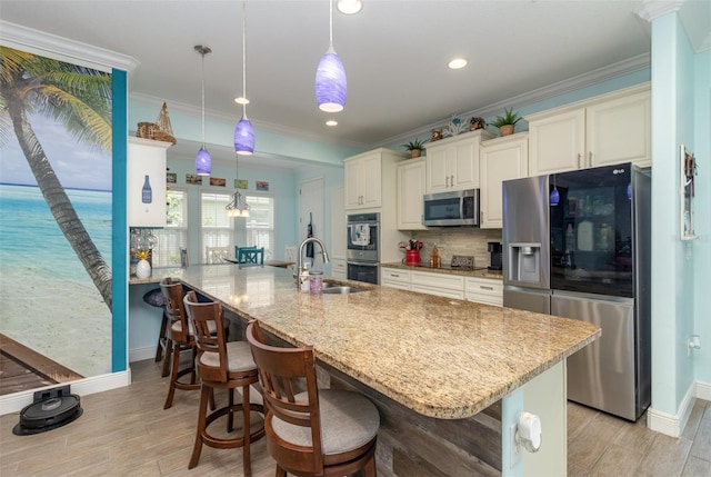 kitchen with hanging light fixtures, sink, stainless steel appliances, a kitchen breakfast bar, and crown molding