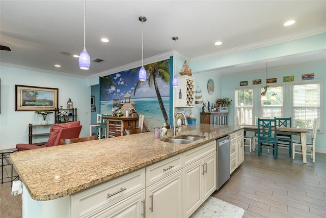 kitchen featuring hanging light fixtures, white cabinets, dishwasher, a center island with sink, and sink