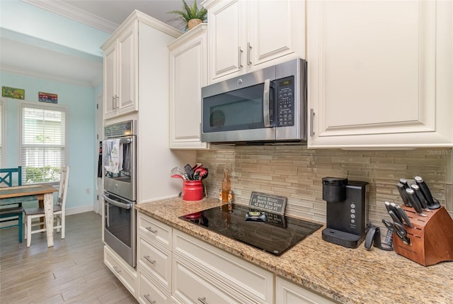 kitchen with black electric cooktop, ornamental molding, tasteful backsplash, and white cabinetry