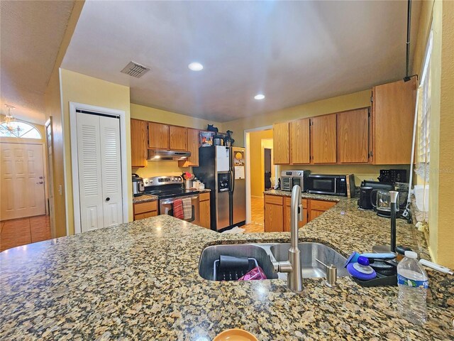 kitchen featuring light tile patterned floors, light stone counters, stainless steel appliances, and sink