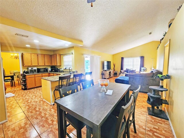 tiled dining space featuring lofted ceiling, sink, and a textured ceiling