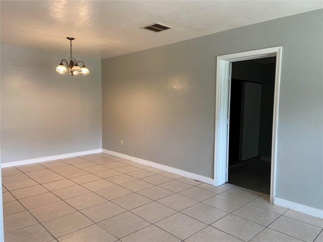 empty room featuring a chandelier and light tile patterned flooring