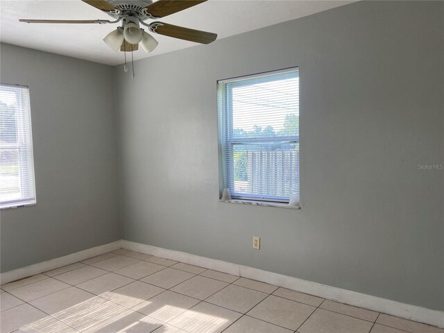 tiled empty room with a wealth of natural light and ceiling fan