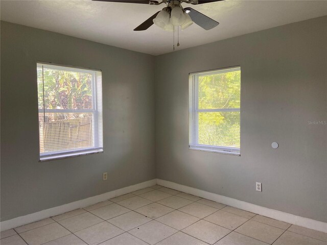 tiled spare room featuring a wealth of natural light and ceiling fan