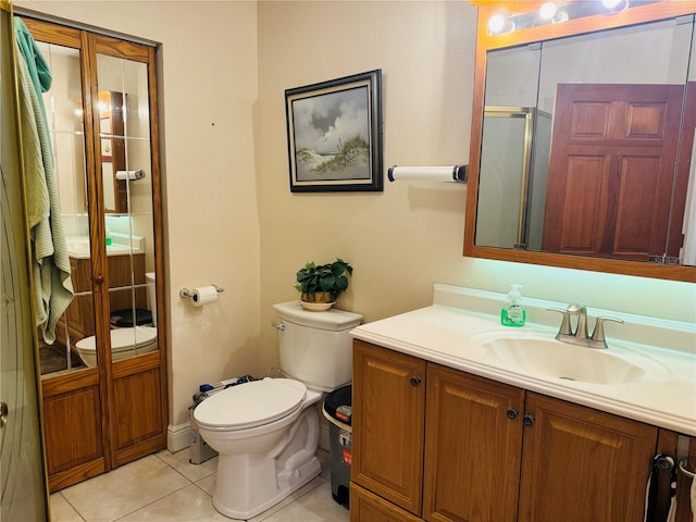 bathroom featuring a shower with door, vanity, toilet, and tile patterned flooring