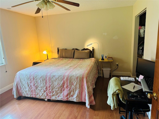 bedroom with ceiling fan, wood-type flooring, and a textured ceiling