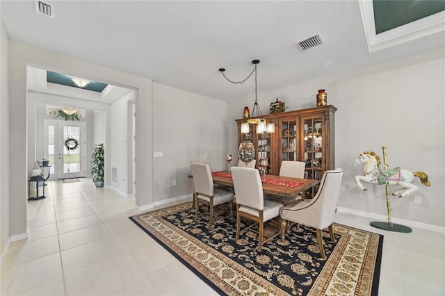 dining space with french doors, a textured ceiling, and light tile patterned floors