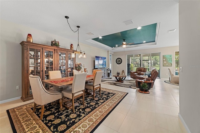 dining space with light tile patterned floors, a raised ceiling, and ceiling fan with notable chandelier