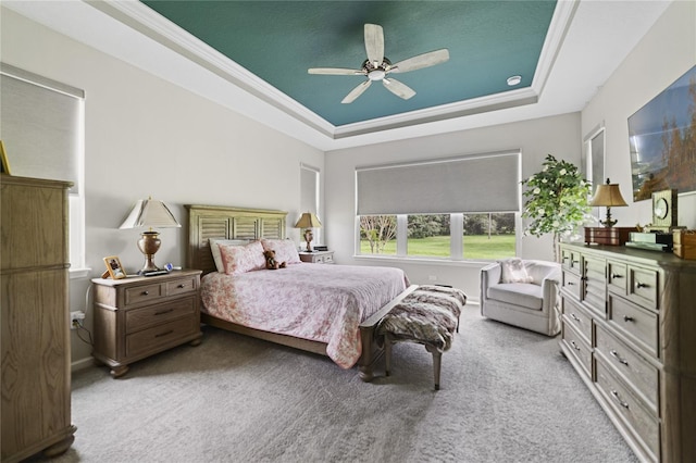 carpeted bedroom with crown molding, ceiling fan, and a tray ceiling