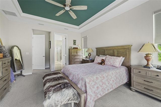 carpeted bedroom with ceiling fan, a raised ceiling, connected bathroom, and ornamental molding