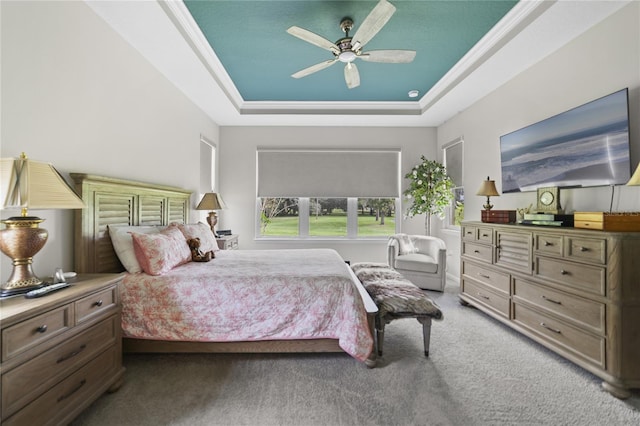 bedroom with a tray ceiling, light colored carpet, ornamental molding, and ceiling fan