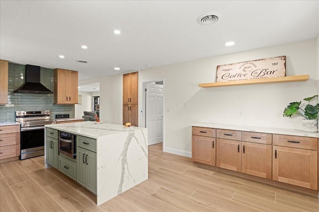 kitchen featuring light stone counters, a center island, wall chimney exhaust hood, appliances with stainless steel finishes, and light hardwood / wood-style floors