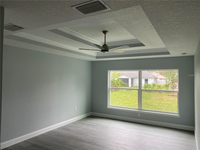 spare room featuring a textured ceiling, a raised ceiling, ornamental molding, hardwood / wood-style flooring, and ceiling fan