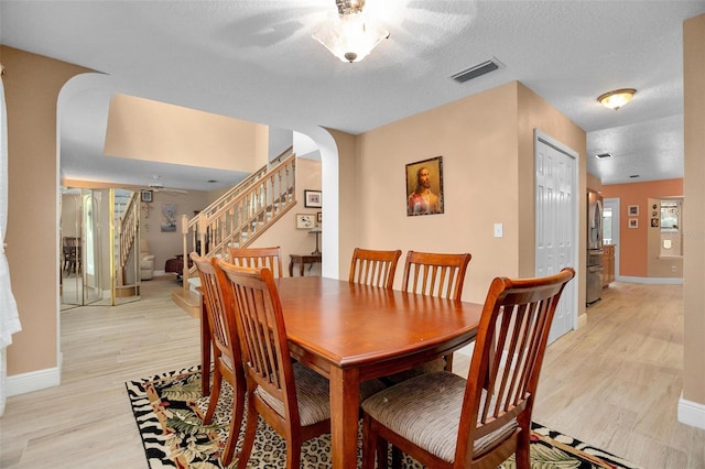 dining area featuring a textured ceiling and light hardwood / wood-style flooring