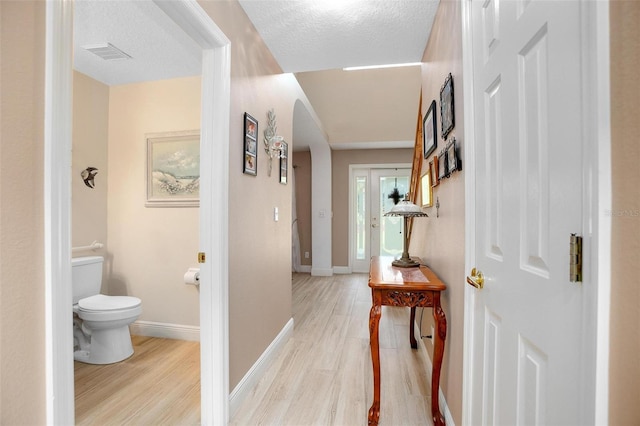 hallway featuring a textured ceiling and light hardwood / wood-style flooring