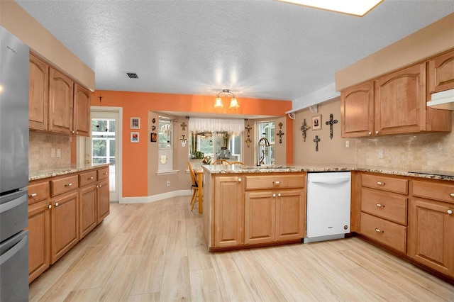 kitchen with dishwasher, stainless steel refrigerator, kitchen peninsula, and sink