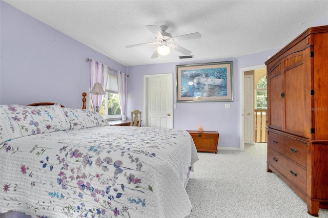 carpeted bedroom featuring ceiling fan and a textured ceiling