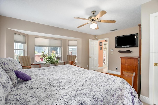 bedroom featuring light wood-type flooring, a textured ceiling, and ceiling fan