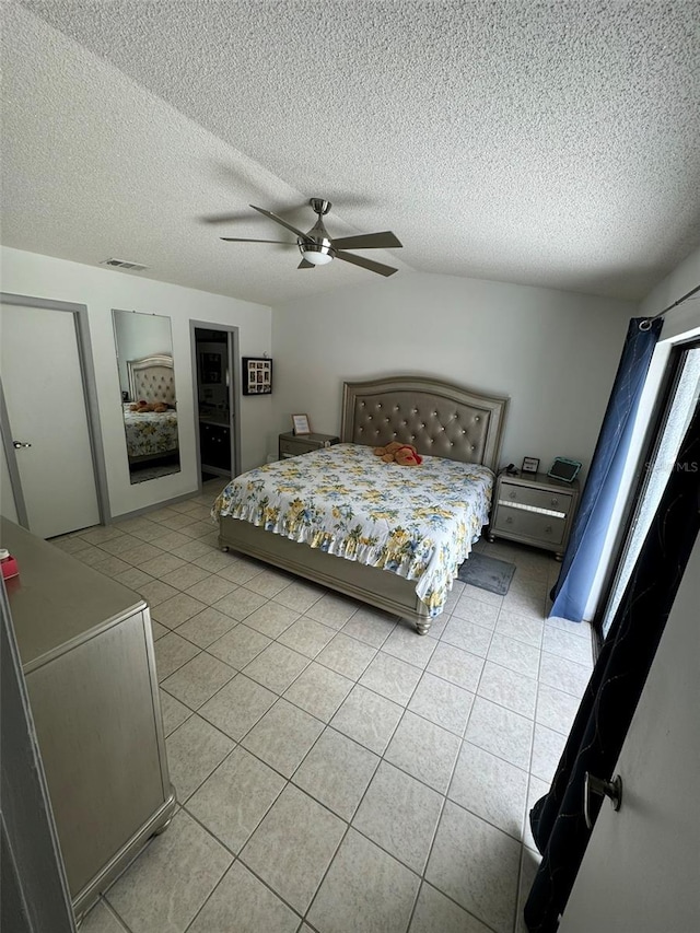bedroom with light tile patterned flooring, a ceiling fan, visible vents, and a textured ceiling