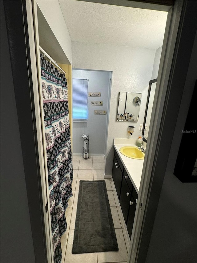 bathroom featuring tile patterned flooring, vanity, a textured wall, and a textured ceiling