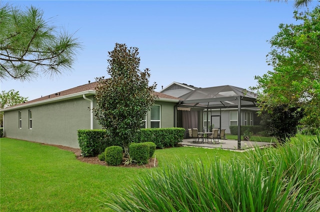 back of house with a lawn, glass enclosure, and a patio area