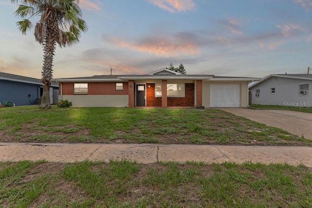 ranch-style house with a garage and a lawn