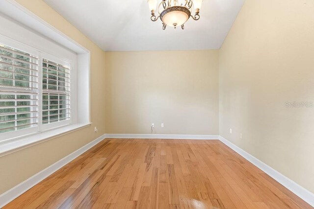 empty room with an inviting chandelier and light hardwood / wood-style floors