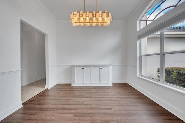 unfurnished dining area with ornamental molding, a notable chandelier, and hardwood / wood-style flooring