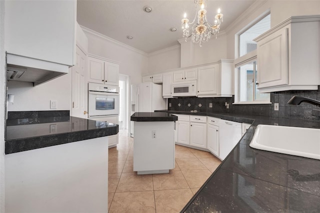 kitchen with a notable chandelier, white cabinetry, white appliances, sink, and a center island